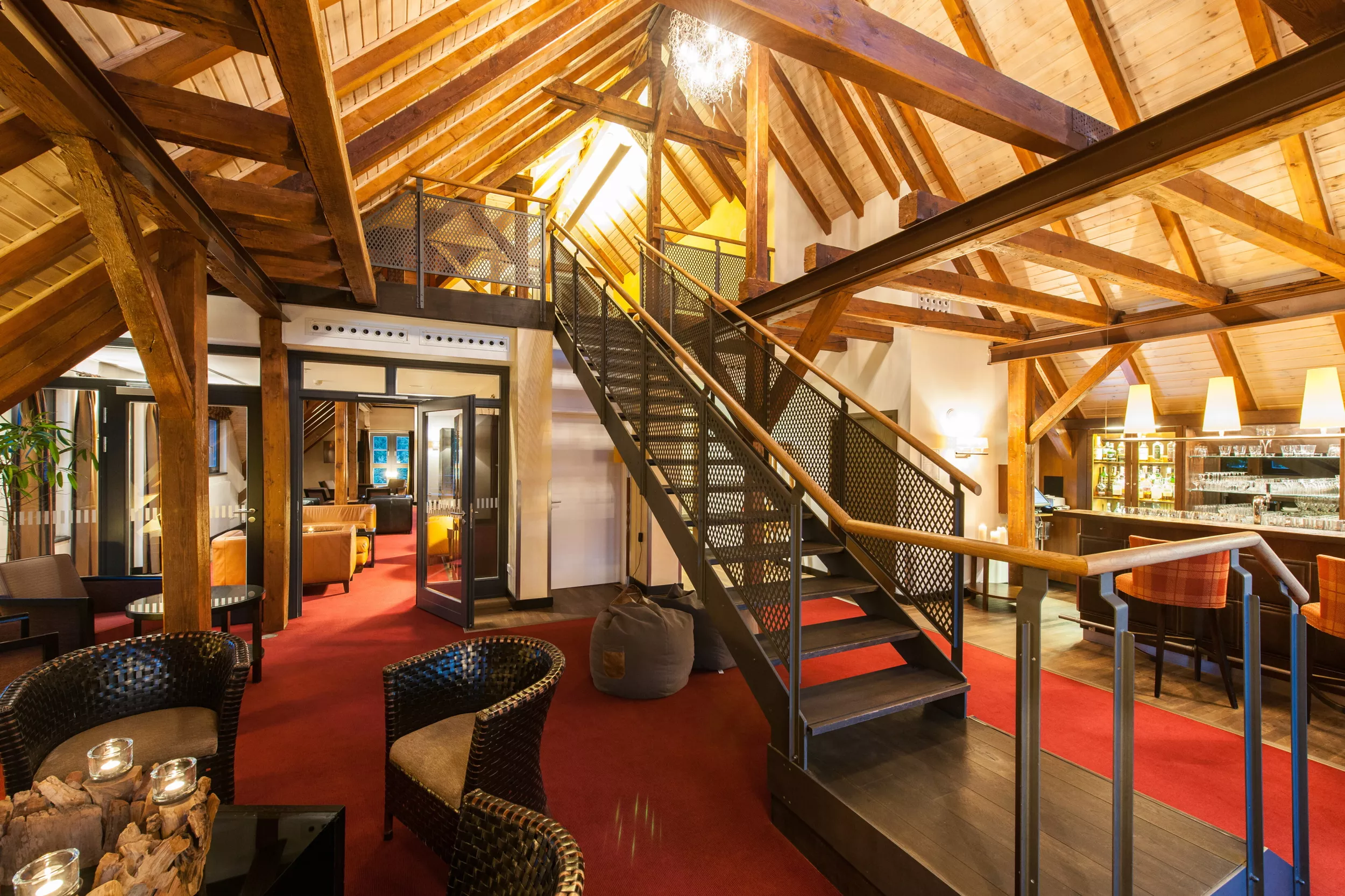 Lounge gemütlich mit offenem Dachstuhl, Bar, Sitzgruppen und Treppe in ein höhergelegenes Séparée.