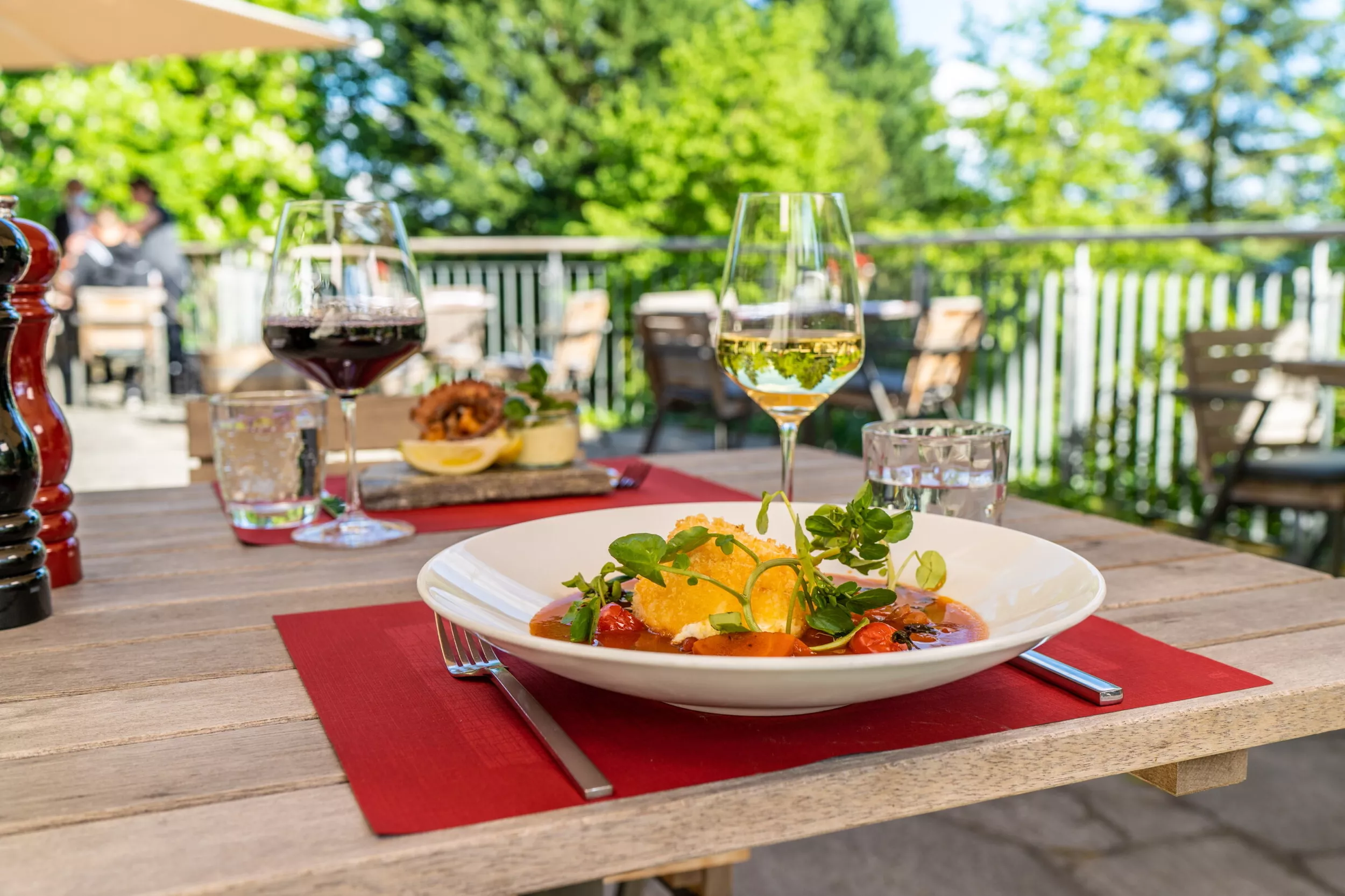 italienisches Nudelgericht auf einem gedeckten Tisch auf der Terrasse, mit Weingläsern