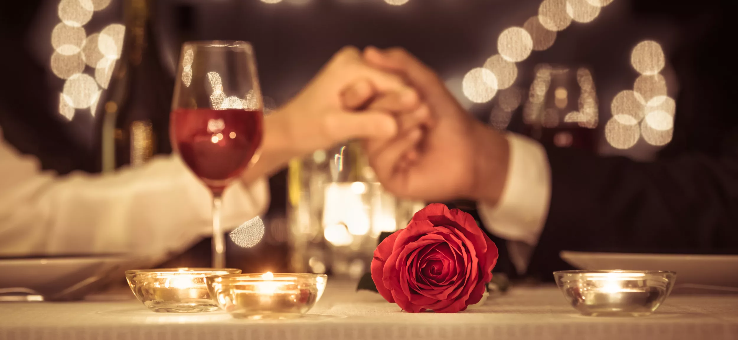 romantisch gedeckter Tisch mit Frau und Mann die sich die Hand halten