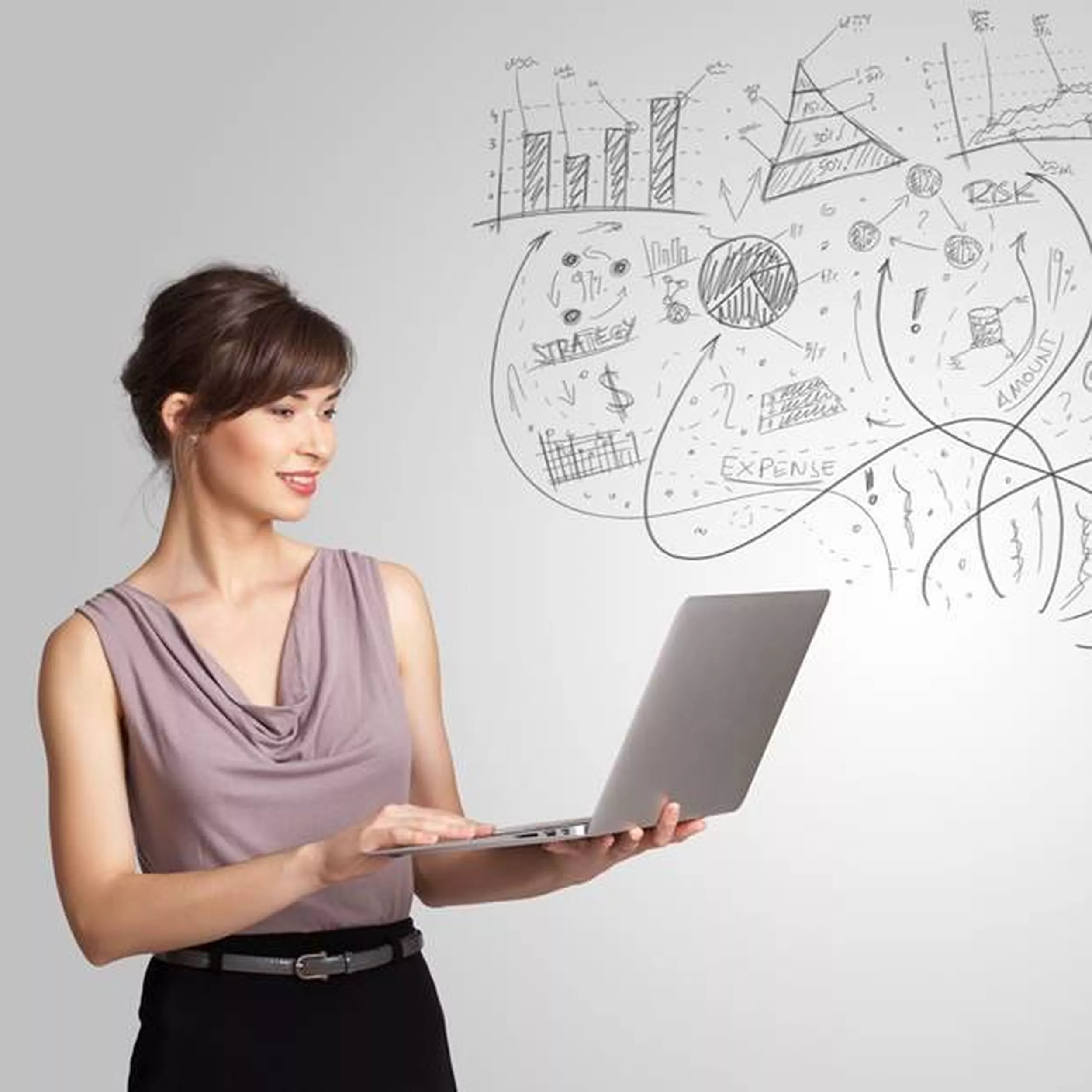 stehende Frau mit aufgeklapptem Laptop auf dem Arm, Graphiken an der Wand hinter ihr